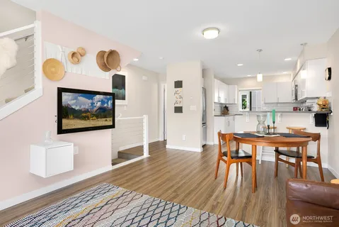 a kitchen with stainless steel appliances granite countertop a stove a refrigerator a kitchen island a table and chairs with wooden floor