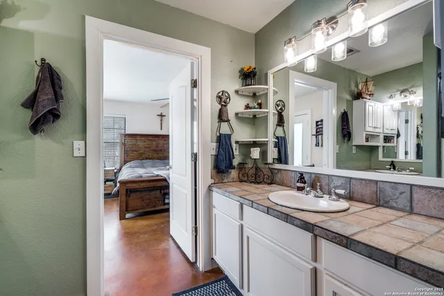a en suite bathroom with a granite countertop sink and a mirror