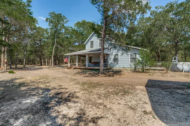 a front view of house with yard and trees in the background
