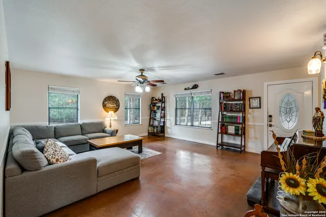 a living room with furniture a ceiling fan and a window
