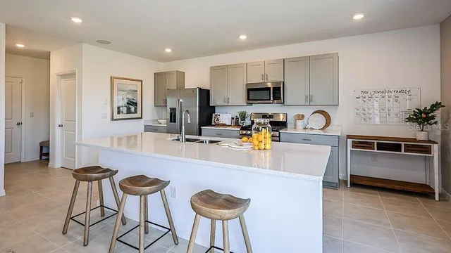 a kitchen with stainless steel appliances granite countertop a stove top oven a sink a refrigerator and white cabinets with wooden floor