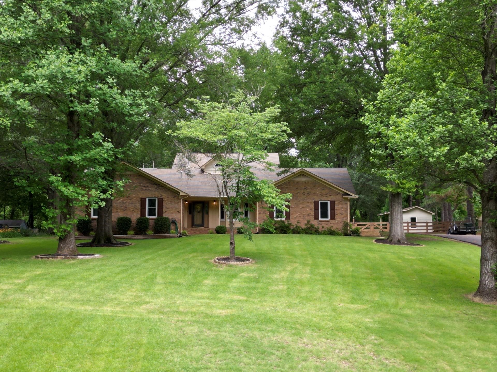 a view of a house with a big yard and large trees