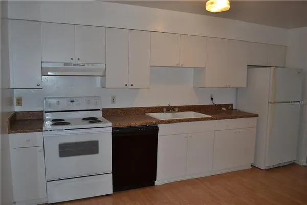a kitchen with granite countertop white cabinets and white stove