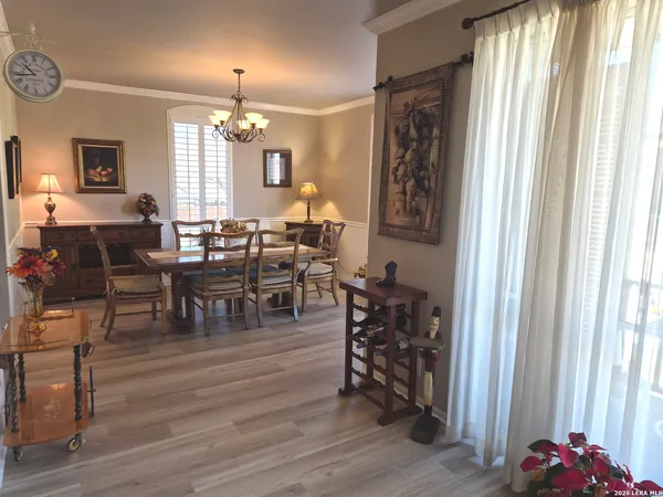 a dining room with wooden floor a chandelier a wooden table and chairs