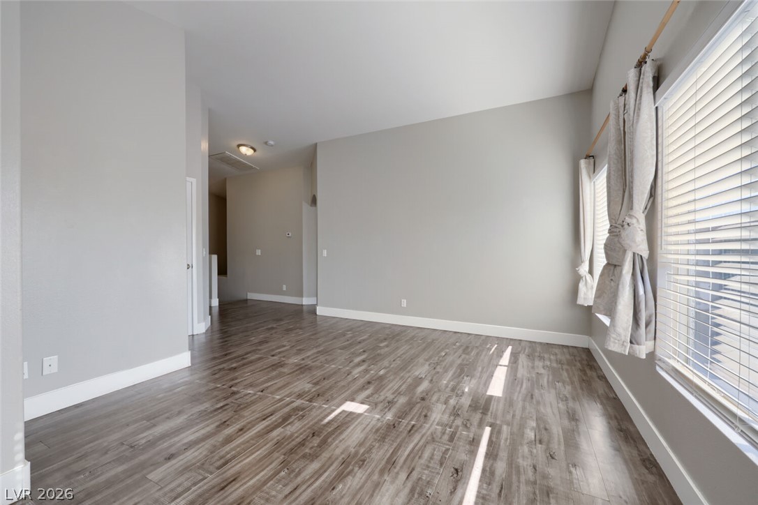 5985 High Steed Street, Unit 101 Henderson, NV 89011 - Photo 7 of 38 Well-lit living area featuring rich wood flooring and tall windows.