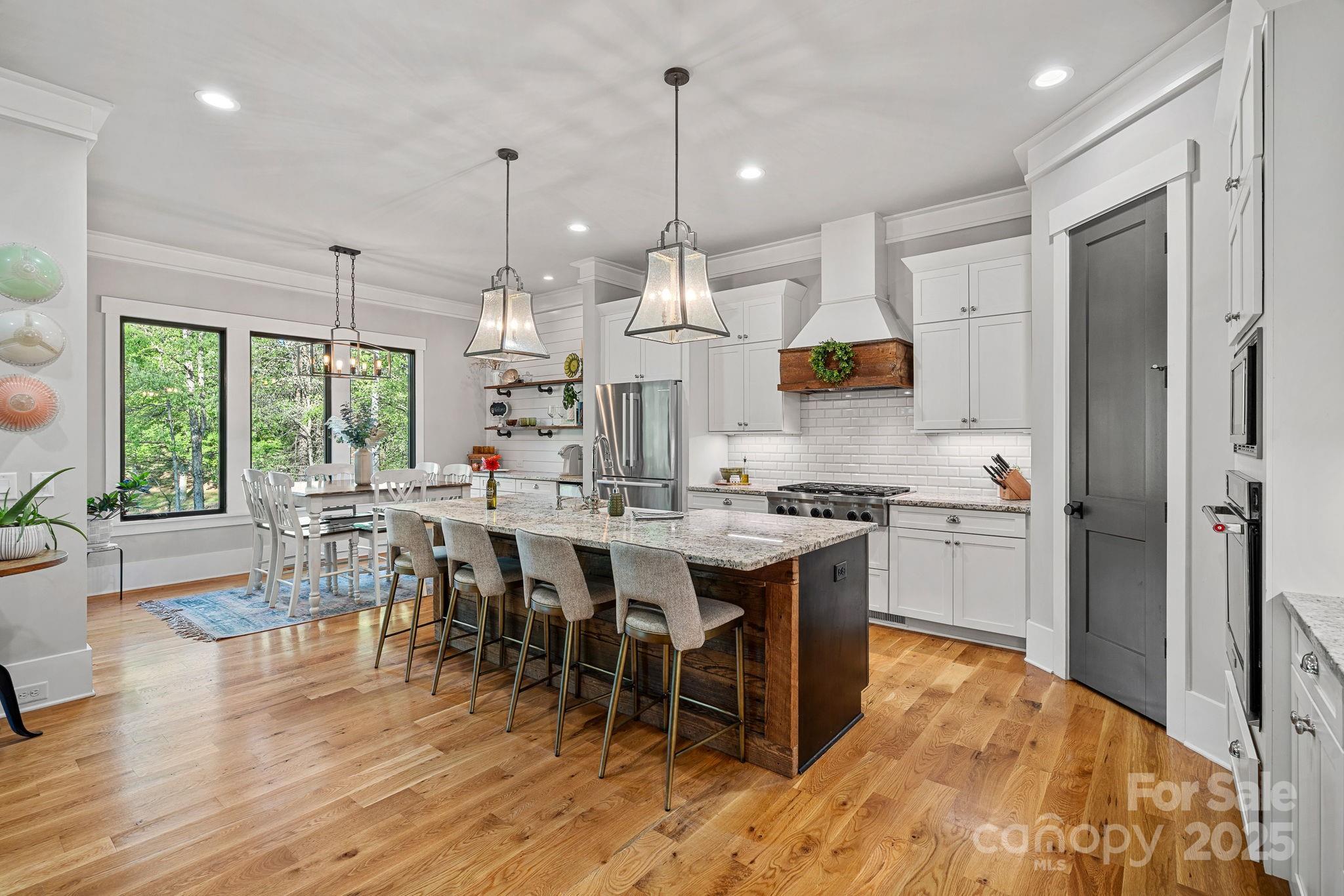 327 Kenway Loop Mooresville, NC 28117 - Photo 11 of 46 a kitchen with stainless steel appliances granite countertop a stove a refrigerator a kitchen island a dining table and chairs with wooden floor