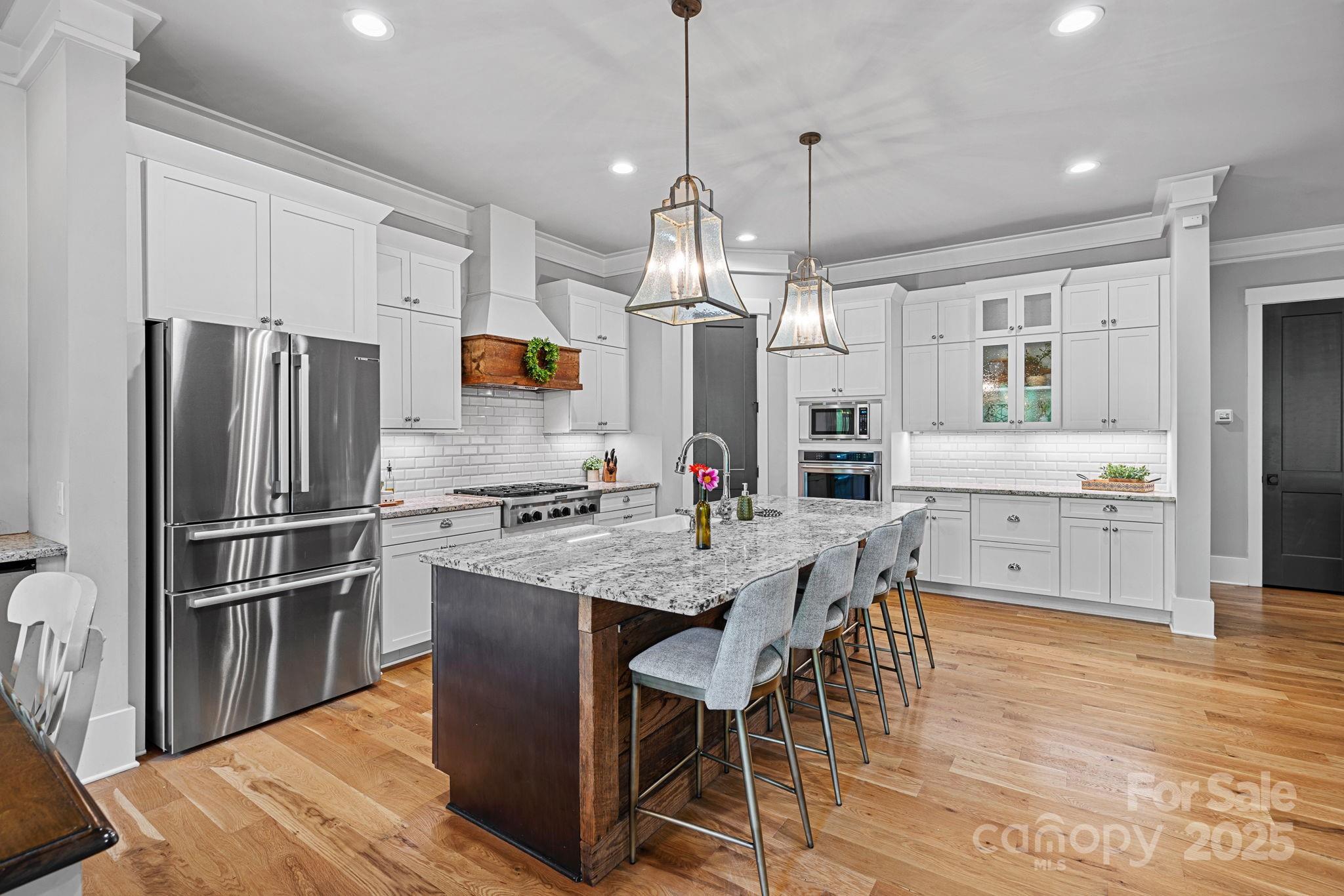 327 Kenway Loop Mooresville, NC 28117 - Photo 12 of 46 a kitchen with stainless steel appliances granite countertop a refrigerator a sink dishwasher a stove and white cabinets with wooden floor