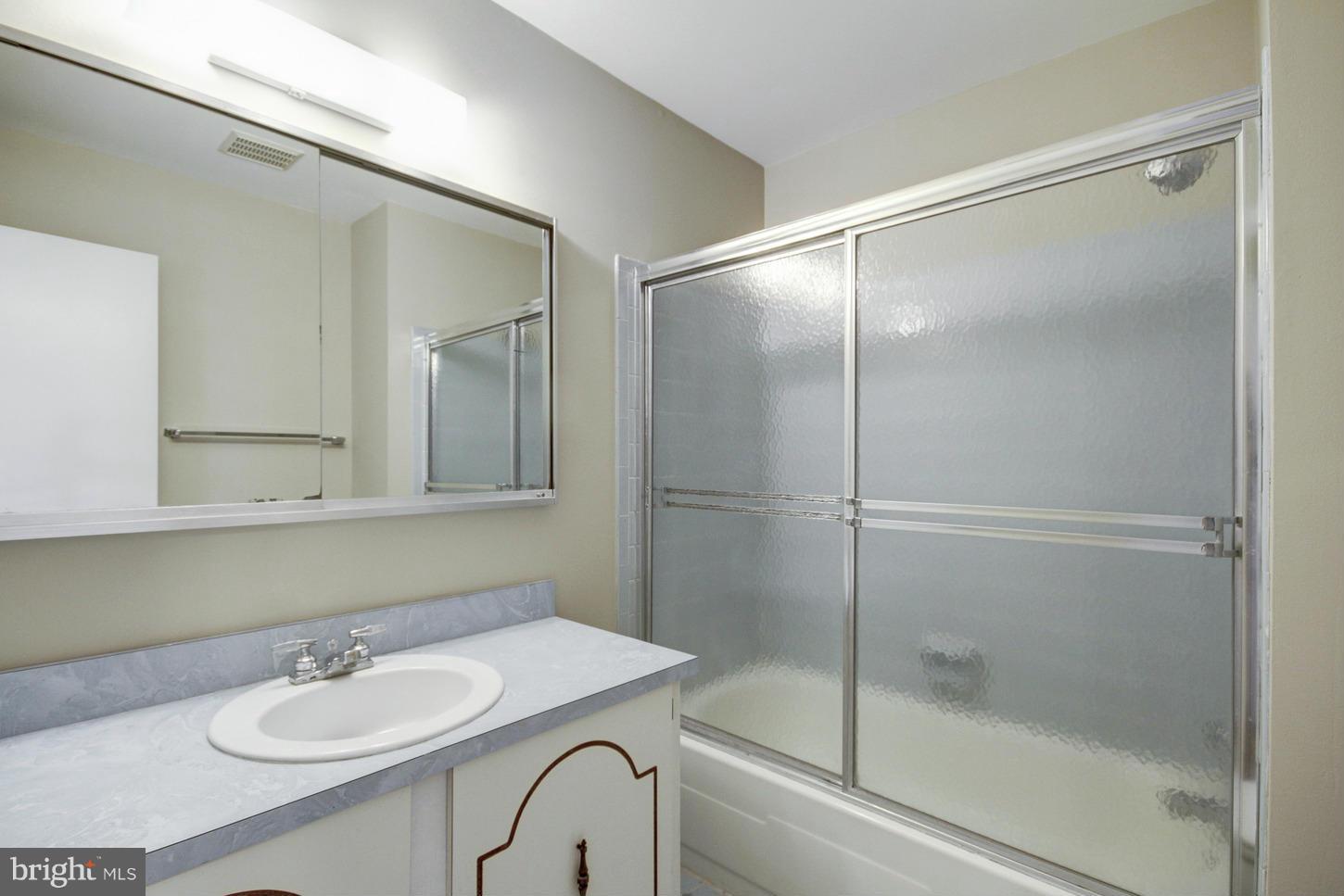 12208 St James Road Potomac, MD 20854 - Photo 18 of 29 a bathroom with a shower sink and mirror