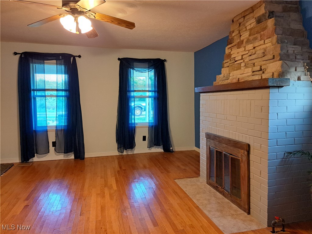 49197 John Tomcho Road Cumberland, OH 43732 - Photo 10 of 50 Unfurnished living room with ceiling fan, a fireplace, and light hardwood / wood-style flooring