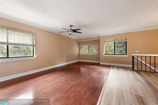 a view of an empty room with a window and wooden floor