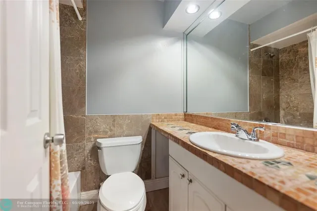 a bathroom with a granite countertop toilet sink and mirror