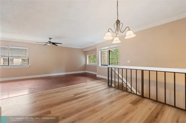 a view of a room with wooden floor fan and windows