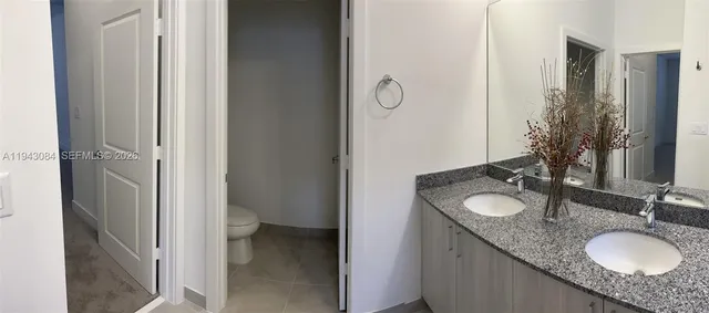 a bathroom with a granite countertop double vanity sink and a mirror