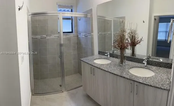 a bathroom with a granite countertop shower sink and mirror