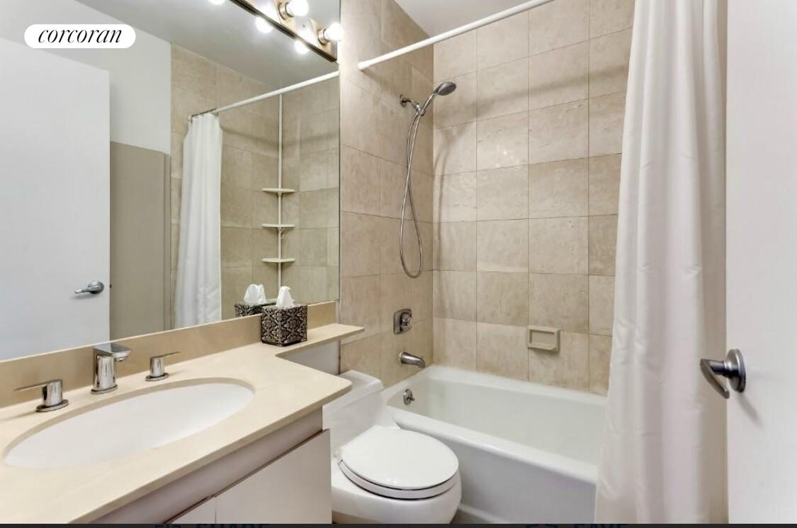 330 East 75th Street, Unit 9D Manhattan, NY 10021 - Photo 3 of 7 a bathroom with a bathtub shower sink vanity mirror and toilet