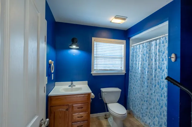 a bathroom with a granite countertop toilet a sink and a mirror