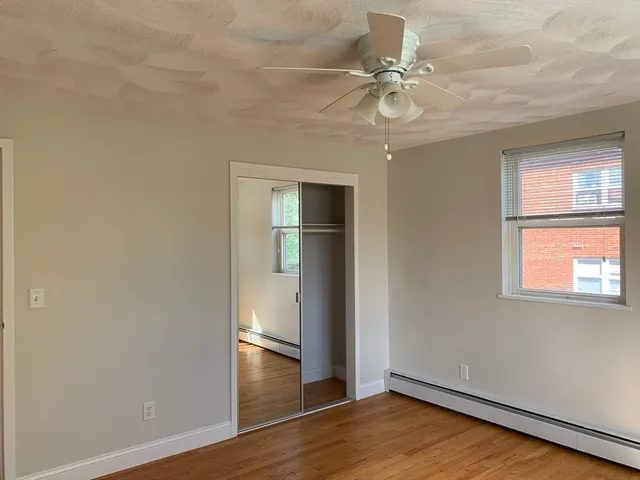 an empty room with wooden floor fan and windows