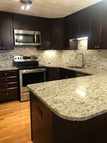 a kitchen with kitchen island granite countertop wooden cabinets and stainless steel appliances