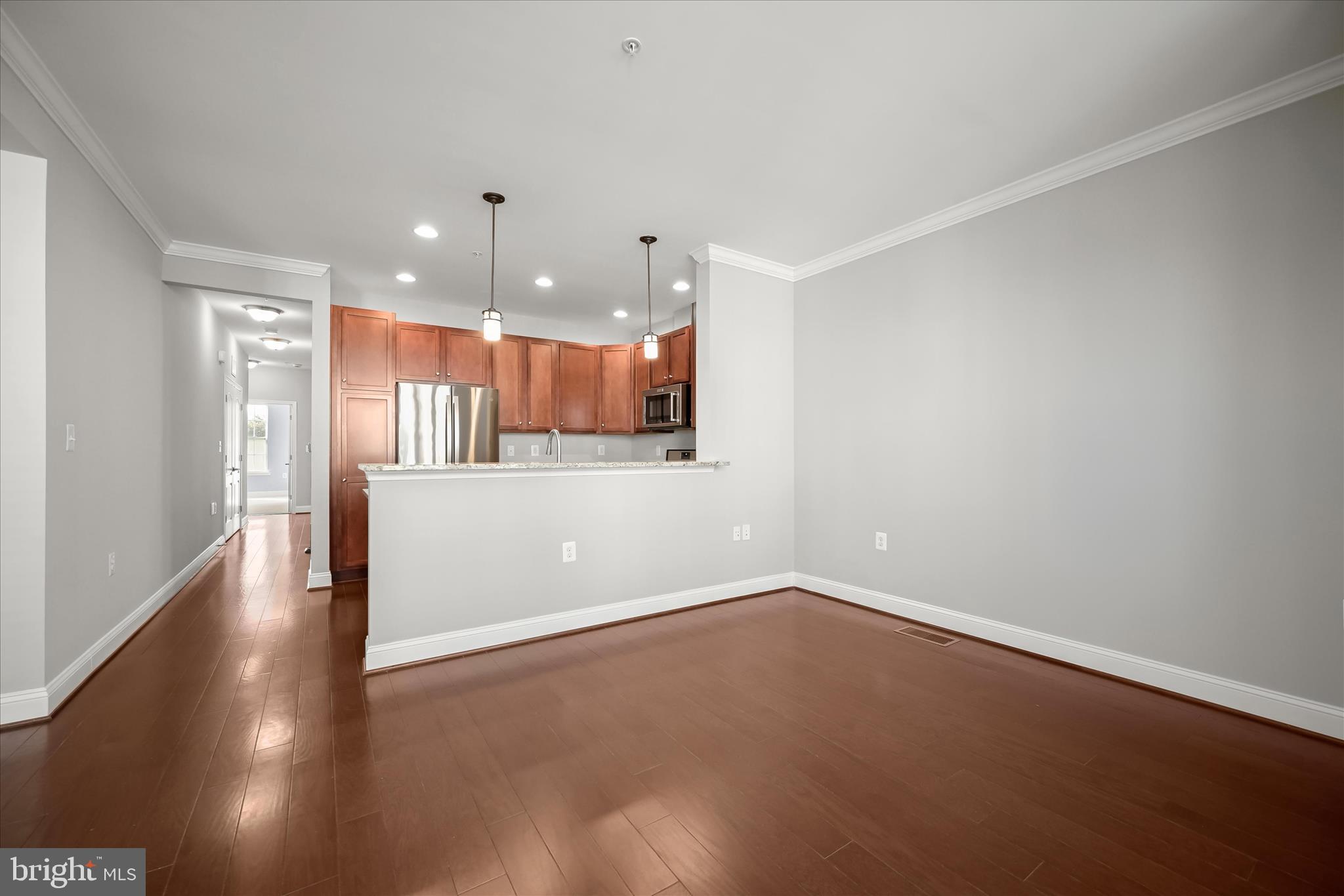 11246-1 Chase Street, Unit 141 Fulton, MD 20759 - Photo 18 of 38 an empty room with a kitchen and wooden floor