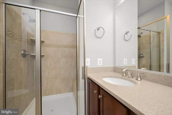 a bathroom with a granite countertop shower sink and mirror