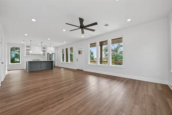 a view of an empty room with a window and wooden floor