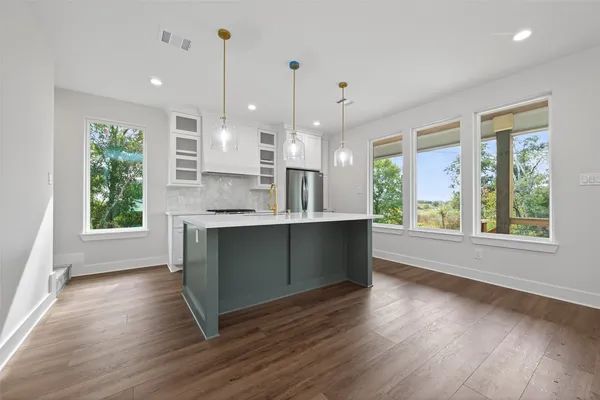 a kitchen with kitchen island granite countertop a stove a sink a large window and wooden floor