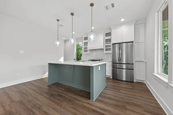 a kitchen with stainless steel appliances a refrigerator a sink and wooden floor