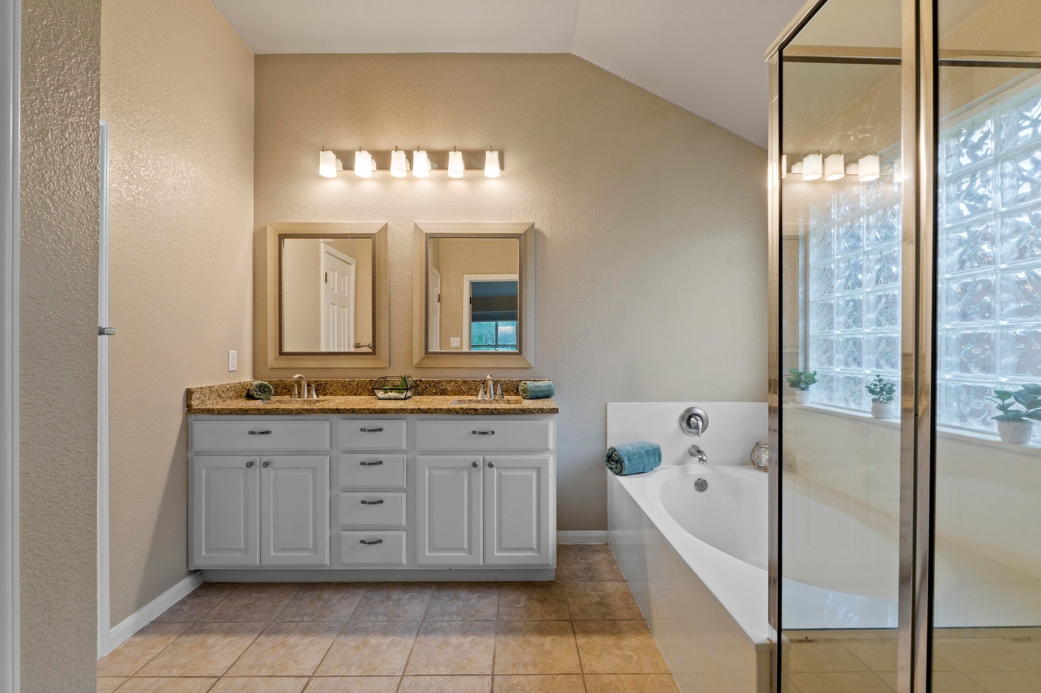 1020 Portchester Castle Path Pflugerville, TX 78660 - Photo 18 of 29 Dual vanities, framed mirrors, and tile flooring grace the primary bathroom.
