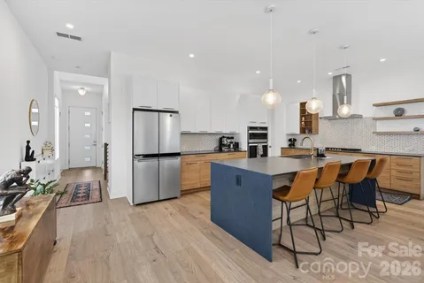 a kitchen with stainless steel appliances granite countertop a refrigerator a sink dishwasher a stove and white cabinets with wooden floor