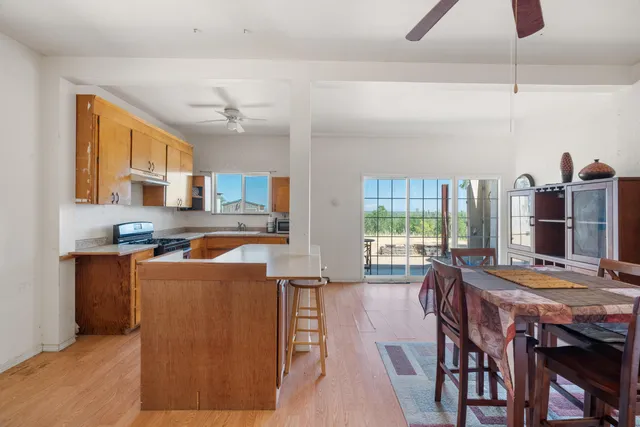 a living room with stainless steel appliances furniture a chandelier wooden floor and a large window