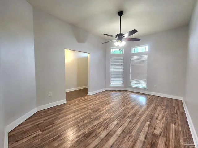 a view of empty room with wooden floor and fan
