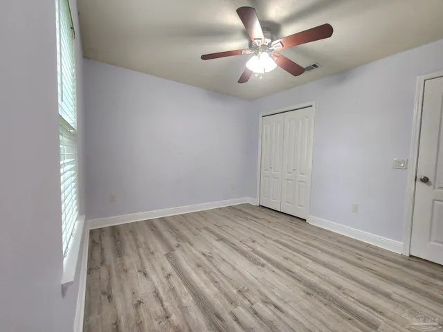 an empty room with wooden floor and ceiling fan