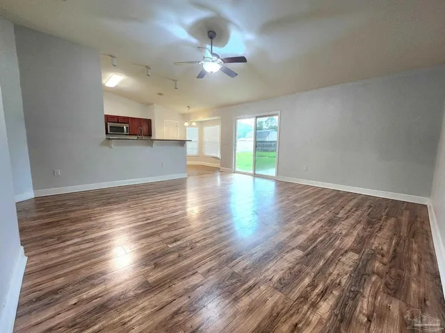 a view of an empty room with a window and wooden floor