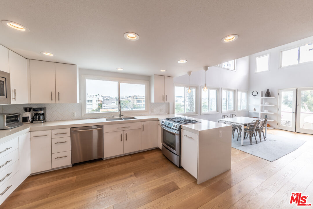 29 Lighthouse Street, Unit 3PH Venice, CA 90292 - Photo 2 of 25 a kitchen with a stove a sink a kitchen island with a dining table and chairs