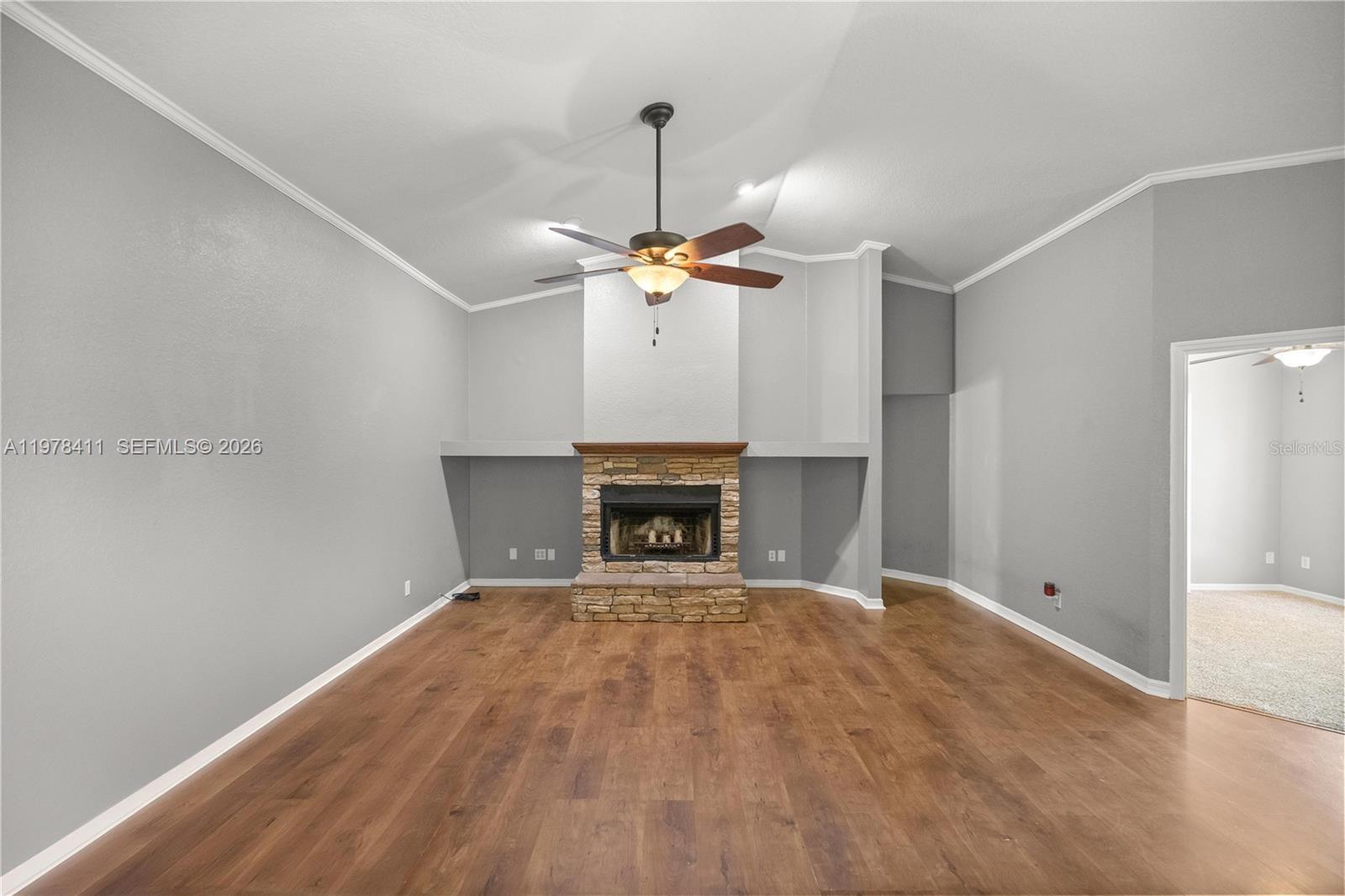 1699 Southwest 80th Street Ocala, FL 34476 - Photo 29 of 47 a view of an empty room with a fireplace and a chandelier fan