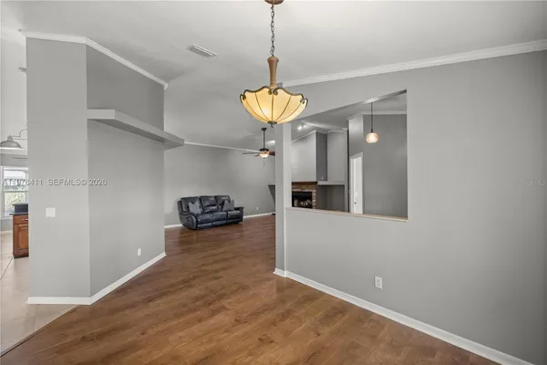 an empty room with wooden floor windows and chandelier