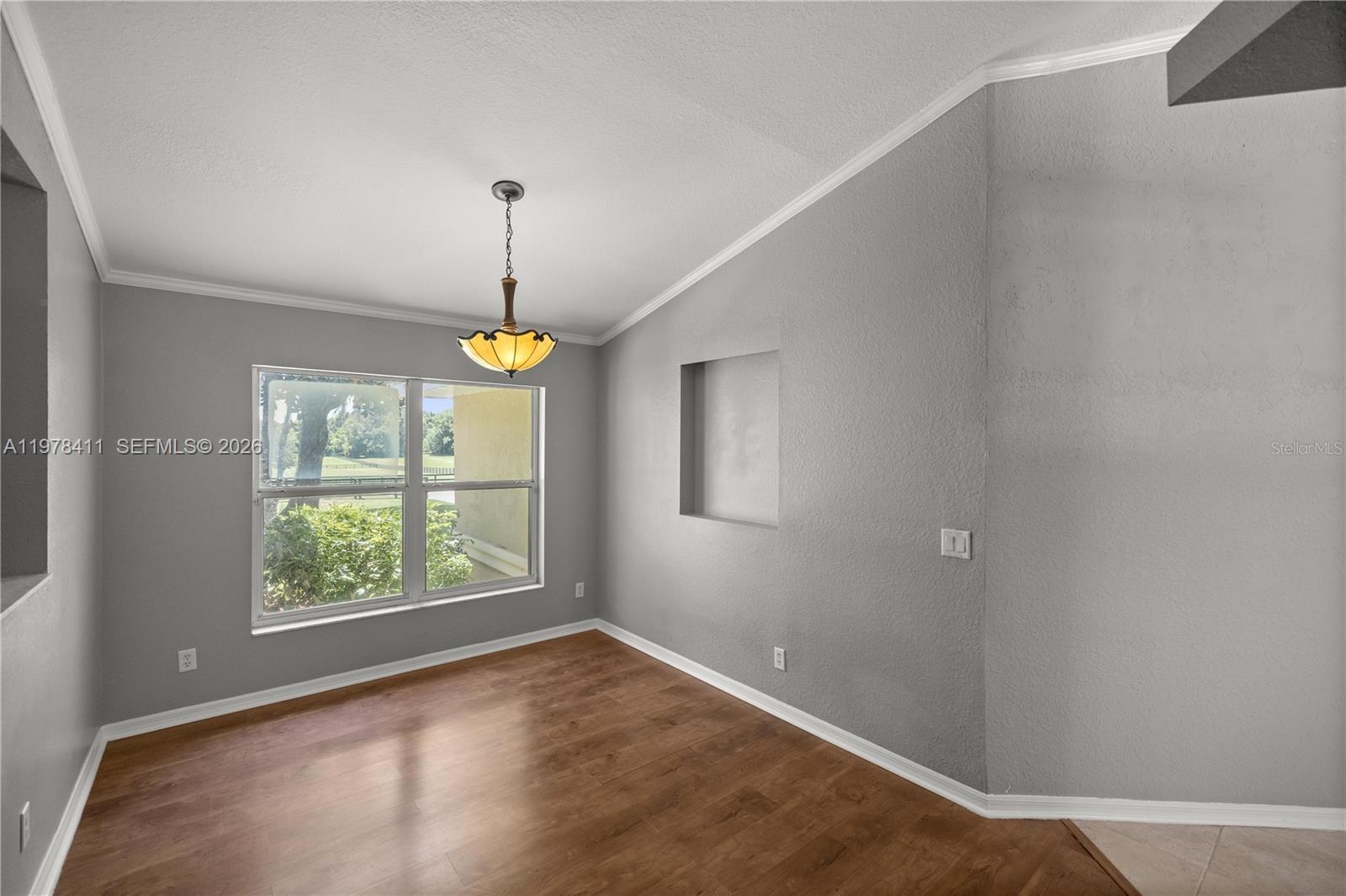 1699 Southwest 80th Street Ocala, FL 34476 - Photo 33 of 47 an empty room with wooden floor windows and chandelier