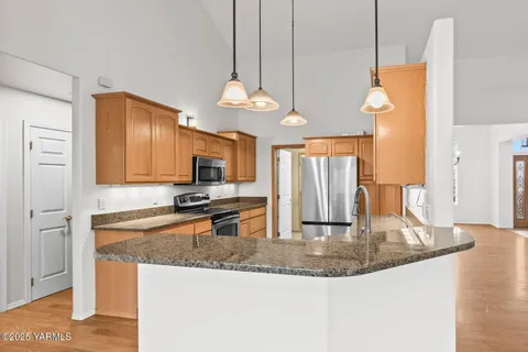 a kitchen with stainless steel appliances granite countertop a stove a sink and a refrigerator
