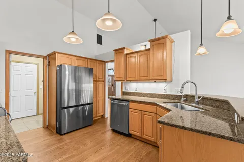 a kitchen with a sink dishwasher a stove and white cabinets with wooden floor
