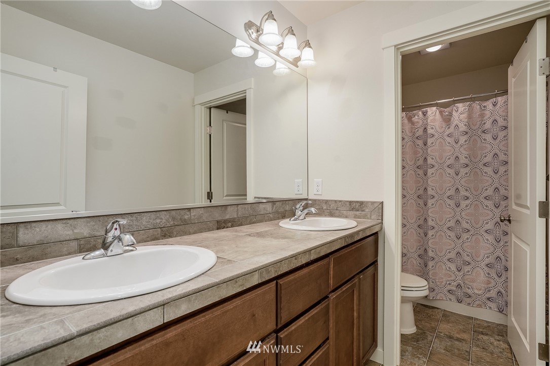 3408 223rd Place Southeast Bothell, WA 98021 - Photo 29 of 40 a bathroom with a granite countertop sink a toilet and a mirror