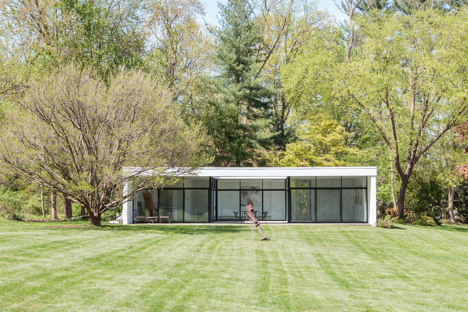 90 Lambert Road New Canaan, CT 06840 - Photo 24 of 28 a front view of a house with a garden and trees