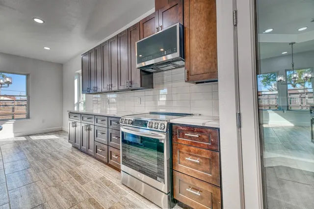 a kitchen with stainless steel appliances granite countertop wooden cabinets and a stove top oven