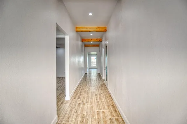 a view of a hallway with wooden floor and a bathroom
