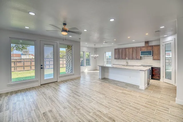 a large kitchen with kitchen island a island wooden floor and stainless steel appliances