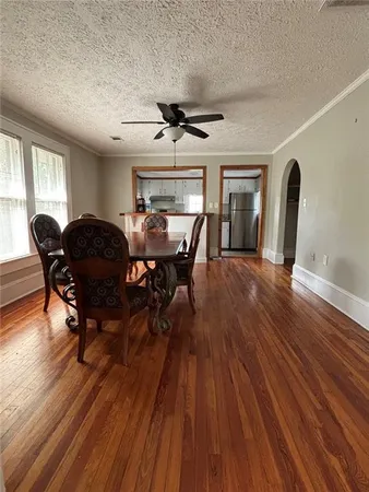 a dining room with wooden floor a chandelier a wooden table and chairs