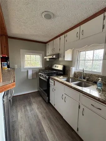 a kitchen with granite countertop a sink cabinets stainless steel appliances and window