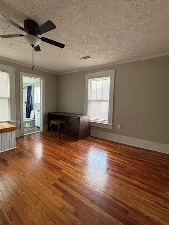 a view of empty room with wooden floor and fan
