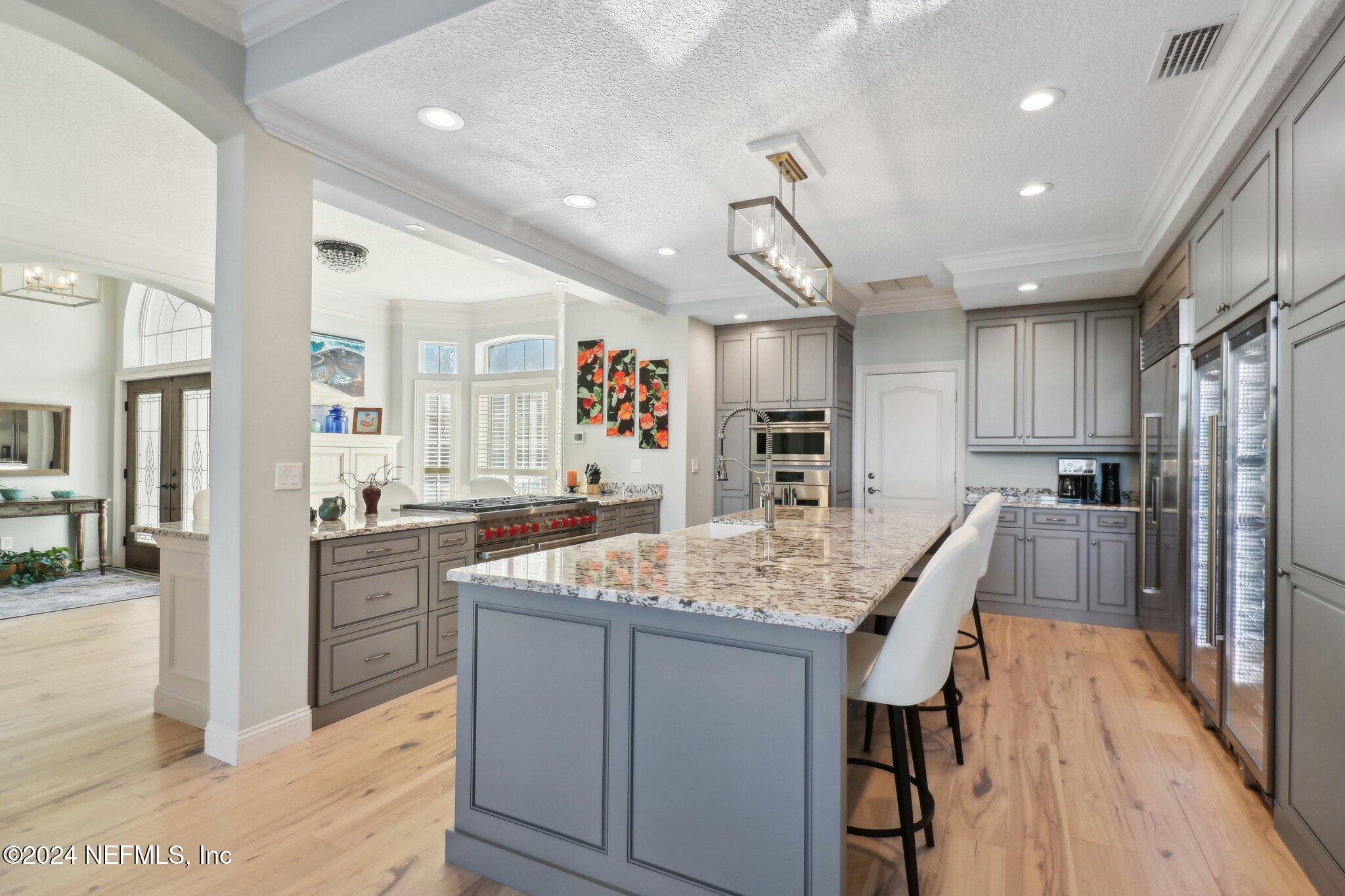 240 Pinehurst Pointe Drive St. Augustine, FL 32092 - Photo 15 of 70 a kitchen with stainless steel appliances kitchen island granite countertop a refrigerator a sink dishwasher and wooden cabinets with wooden floor
