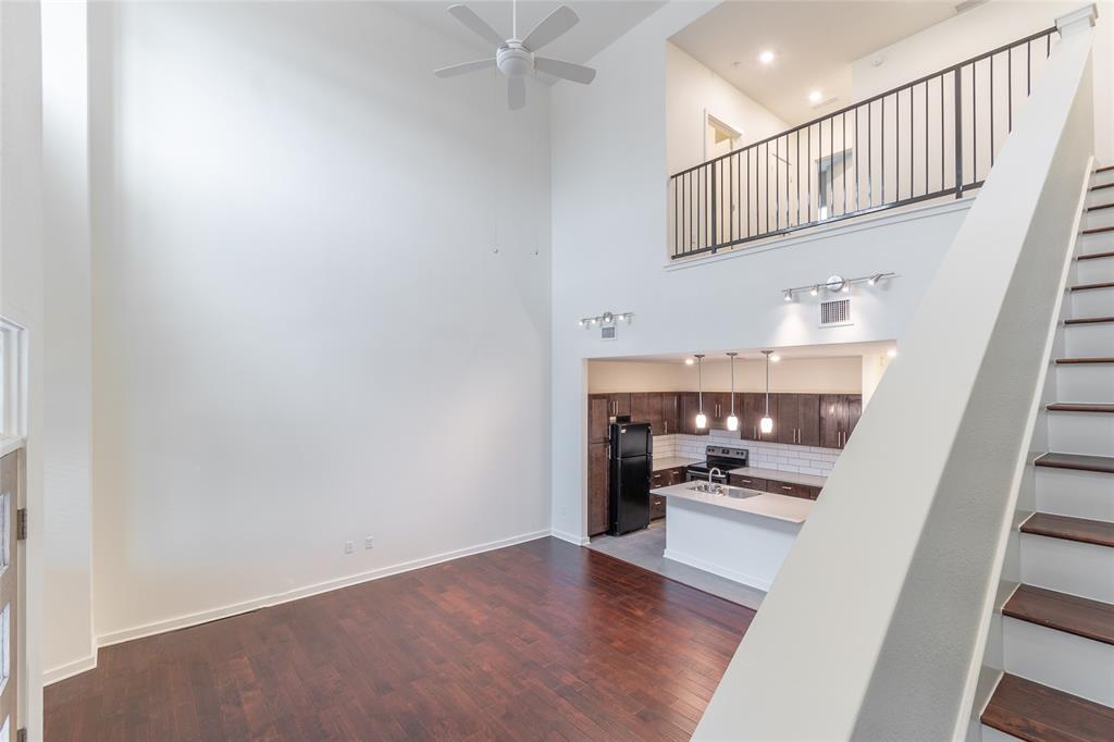 Unfurnished living room featuring a high ceiling, stairs, dark wood finished floors, and ceiling fan