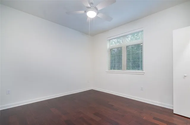 a view of an empty room with a window and wooden floor